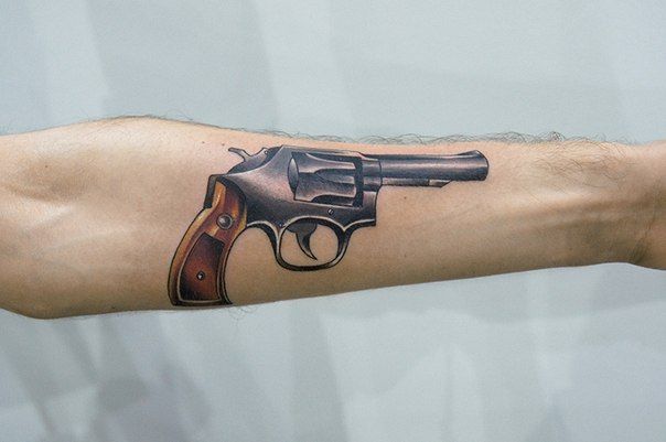 Небольшая тату револьвер на руке