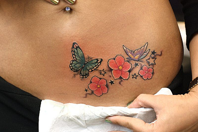 Татуировка бабочки с цветком на животе